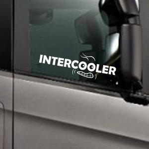 May include: White vinyl decal with the text "INTERCOOLER" and a cartoon image of a smiling mouth with a swirl of air coming out of it. The decal is on the window of a grey truck.