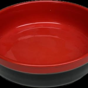 May include: A red and black ceramic baking dish with two handles. The dish is round and has a smooth, glossy finish.
