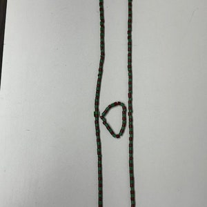 May include: A green and red beaded necklace and bracelet set. The necklace is long and the bracelet is short.