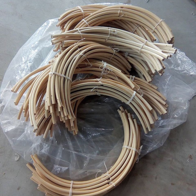 May include: A bundle of natural, light brown, wooden hoops, tied together with string. The hoops are all the same size and shape, and they are arranged in a circular pattern.
