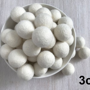 May include: A bowl filled with white felt balls, each measuring 3 cm in diameter. The balls are arranged in a random pattern and are all the same size.