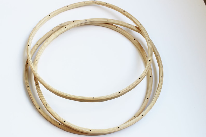 May include: Three wooden hoops with small holes drilled around the circumference. The hoops are stacked on top of each other.