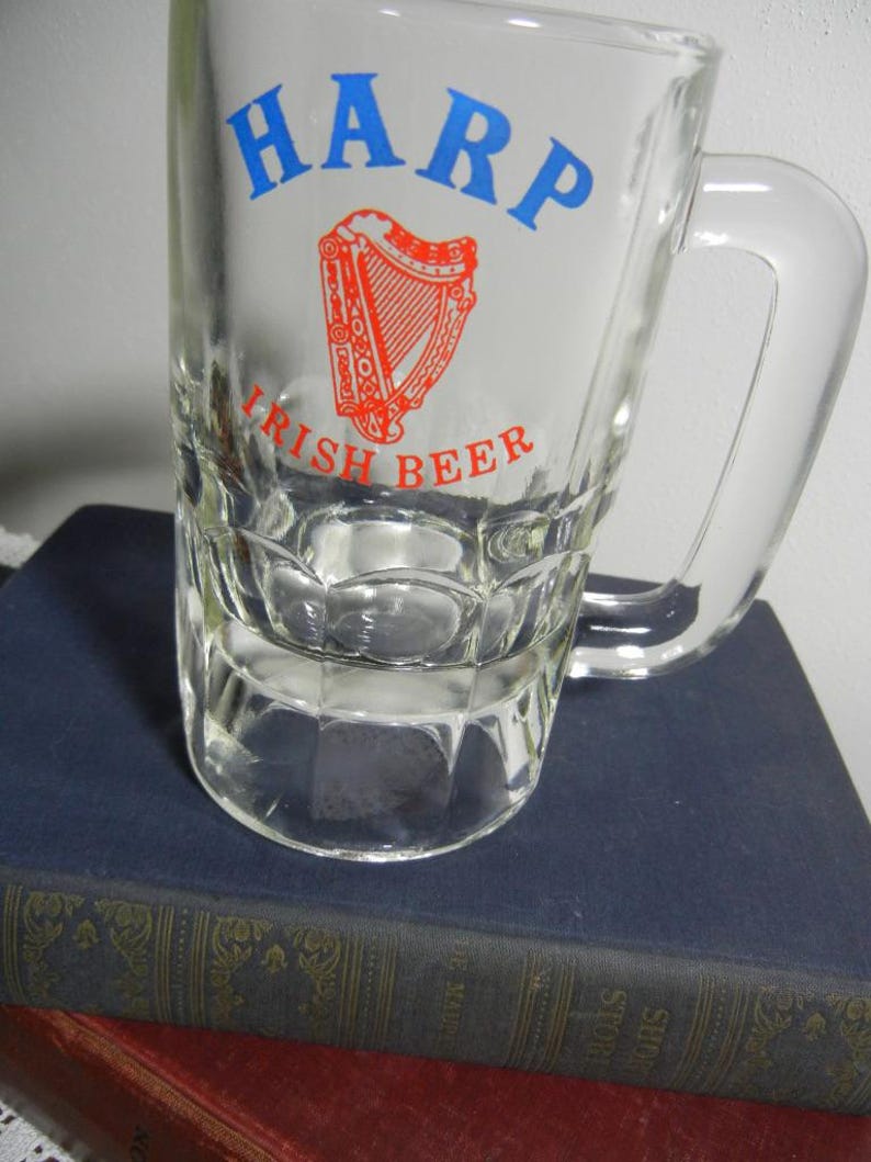 May include: Clear glass beer mug with a handle. The mug features the word "HARP" in blue, above a red and white harp graphic, and the words "IRISH BEER" in red.