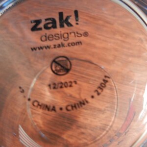 May include: Clear glass cup with the text "zak! designs" and "www.zak.com" printed in black. The bottom of the cup has a circular stamp with the text "12/2021", "CHINA", and "23041".