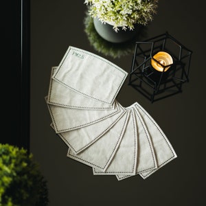 May include: A stack of eight white PM2.5 air filter replacements. The filters are rectangular and have a black stitched border.