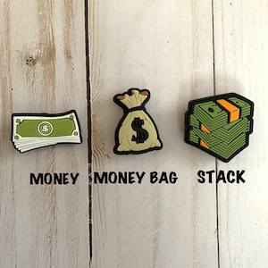 Könnte beinhalten: Drei grüne und gelbe Glücksbringer zum Thema Geld. Der erste Glücksbringer ist ein Stapel Geldscheine, der zweite ist ein Geldbeutel und der dritte ist ein Stapel Geldscheine.