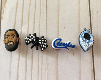 Könnte beinhalten: Vier Schuhcharms mit einer schwarz-weißen karierten Flagge, einem blau-weißen Bandana, einem schwarz-braunen Cartoon-Porträt eines Mannes mit Bart und einem weiß-blauen Logo mit der Aufschrift "Cresshaw".
