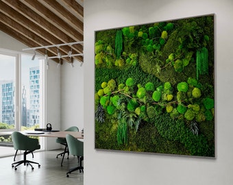 May include: A green moss wall art piece with a variety of textures and shades of green. The moss is framed in a thin, silver frame and is hanging on a white wall.