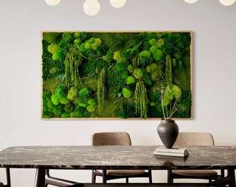 May include: A green moss wall art piece hangs above a dark marble dining table with two chairs. The moss wall art is framed in wood and features a variety of green moss textures.