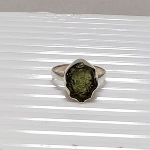 Pu&ograve; includere: Un anello d'argento con una pietra preziosa verde grezza. La pietra &egrave; incastonata in una fascia d'argento e ha una forma irregolare unica.