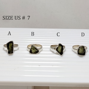 Pu&ograve; includere: Quattro anelli d'argento con pietre preziose verdi. Gli anelli sono etichettati con le lettere A, B, C e D. Il testo "SIZE US # 7" &egrave; nella parte superiore dell'immagine.