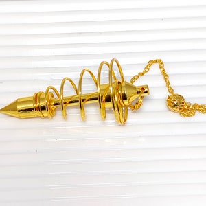 May include: A gold-coloured metal pendulum with a spiral design and a pointed tip. It is attached to a gold chain with a small ball at the end.