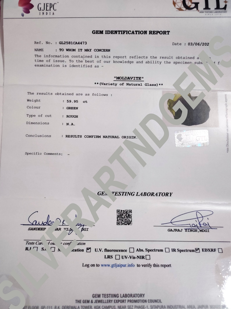 Pu&ograve; includere: Un rapporto di identificazione di gemma per una Moldavite verde, del peso di 59,95 carati, con taglio grezzo. Il rapporto afferma che la gemma &egrave; naturale e ne conferma l'origine. Il rapporto &egrave; datato 03/06/202 e include il nome "GTL" per Gem Testing Laboratory.