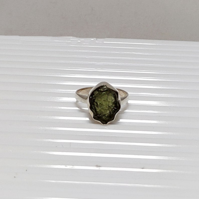 Pu&ograve; includere: Un anello d'argento con una pietra preziosa verde grezza. La pietra &egrave; incastonata in una fascia d'argento e ha una forma irregolare unica.