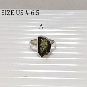 Pu&ograve; includere: Un anello d'argento con una pietra preziosa verde. L'anello &egrave; taglia US #6.5. La pietra preziosa ha una forma irregolare e grezza.