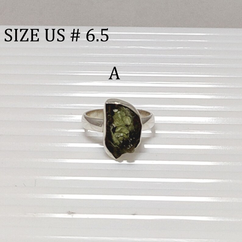 Pu&ograve; includere: Un anello d'argento con una pietra preziosa verde. L'anello &egrave; taglia US #6.5. La pietra preziosa ha una forma irregolare e grezza.