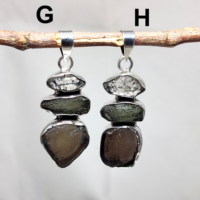 May include: Two silver pendants labelled G and H, each featuring three stacked, raw, irregular gemstones in clear, olive green, and dark brown tones, set in polished silver bezels with a silver bail at the top for hanging on a chain.