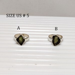 Pu&ograve; includere: Due anelli d'argento con pietre preziose verdi. Gli anelli sono etichettati A e B. Il testo "SIZE US # 5" &egrave; in alto nell'immagine.