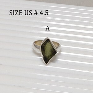 Pu&ograve; includere: Un anello d'argento con una pietra preziosa verde incastonata a forma di diamante. L'anello &egrave; di misura US # 4.5. L'anello &egrave; su uno sfondo bianco.