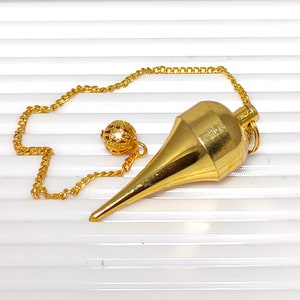 Peut inclure: Un pendule en forme de pointe dorée avec une boule décorative au bout de la chaîne.