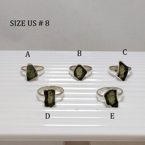 Pu&ograve; includere: Cinque anelli d'argento con pietre preziose verdi. Gli anelli sono etichettati con le lettere A, B, C, D ed E. Il testo "SIZE US # 8" &egrave; nella parte superiore dell'immagine.