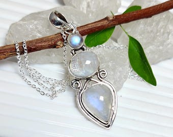 May include: A silver pendant necklace featuring three iridescent moonstone gems. The pendant has a teardrop shape at the bottom, a round center stone, and a small round stone at the top. The necklace chain is delicate.