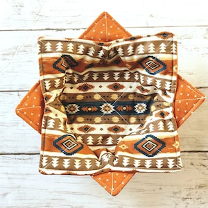 Peut inclure: Un bol en tissu brun et orange avec un motif g&eacute;om&eacute;trique. Le bol est pli&eacute; et pr&ecirc;t &agrave; &ecirc;tre utilis&eacute;.