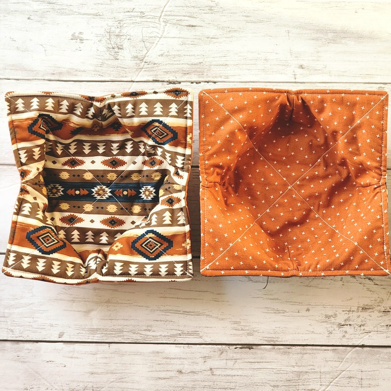 Peut inclure: Deux paniers &agrave; pain en tissu, l'un avec un motif g&eacute;om&eacute;trique en brun, beige et bleu, et l'autre avec un motif blanc et orange.