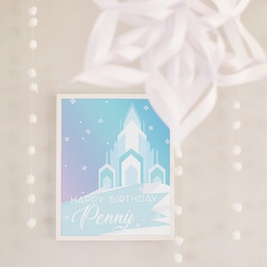 May include: A white framed print with a blue and purple gradient background. The print features a silhouette of an ice castle and the text "Happy Birthday Penny".