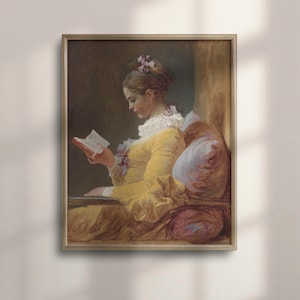 Könnte beinhalten: Gerahmter Kunstdruck eines klassischen Gemäldes. Das Kunstwerk zeigt eine Person in einem gelben Kleid, die ein Buch liest. Die Person sitzt, mit einem weißen Kissen und einer rosa Schleife im Haar. Das Gemälde hat eine warme Farbpalette.