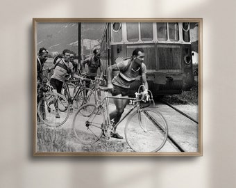 May include: Black and white photograph of a group of cyclists racing on a road with a train in the background. The cyclists are wearing vintage cycling gear and riding bicycles with drop handlebars. The train is a vintage electric train with a single car.