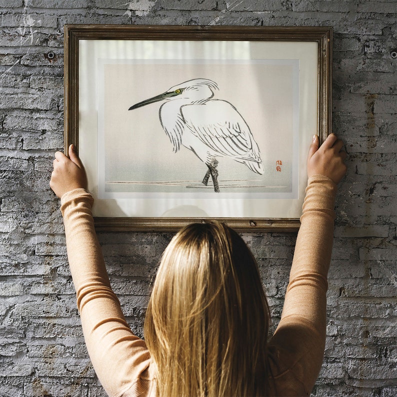 May include: A framed print of a white egret bird with a yellow beak standing on a branch. The print is in a wooden frame with a light brown finish.