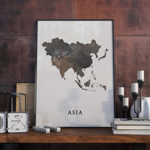May include: A black framed poster featuring a watercolour map of Asia in shades of brown and grey. The word "ASIA" is printed in black at the bottom of the poster.