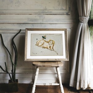May include: A vintage illustration of the constellation Aries, depicted as a ram with a green beetle flying above it. The illustration is framed in a light wood frame and is displayed on a wooden stool.