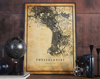 May include: A vintage-style map print of Thessaloniki, Greece. The map is in black and white and features a detailed street network. The city name and coordinates are printed at the bottom of the map.