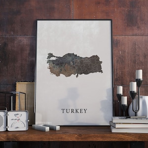May include: A black framed poster with a watercolor map of Turkey in shades of brown, gray, and blue. The word "TURKEY" is printed in black at the bottom of the poster.
