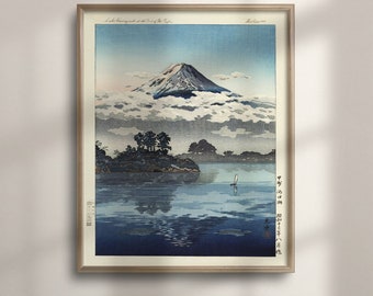 May include: A woodblock print of Mount Fuji reflected in a lake with a small boat in the distance. The print is framed in a light wood frame. The text "Lake Showing under the Crest of the Fuji" is in the top left corner of the print.