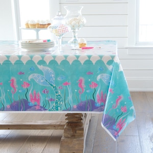 Puede incluir: Un mantel de plástico turquesa con una cola de sirena, caballitos de mar y un diseño de arrecife de coral rosa y morado. El mantel es perfecto para una fiesta con temática de sirenas.
