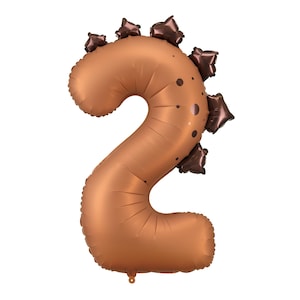 May include: A bronze-coloured number two balloon, styled as a dinosaur. It features dark brown accents, such as spots and spiky shapes along the top. This balloon is designed to create a festive and playful look for a birthday celebration.