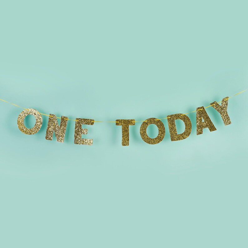 Pu&ograve; includere: Lettere di glitter dorate che compongono la scritta "ONE TODAY" infilate su uno sfondo blu chiaro.