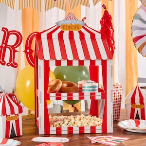 May include: A red and white striped circus-themed concession stand with popcorn, doughnuts, and cake. The sign reads "Welcome to the Circus". Other circus-themed decorations include balloons and a small circus tent.