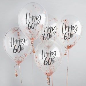 May include: Five clear balloons with rose gold confetti and the text "Happy 60th" printed on each balloon.