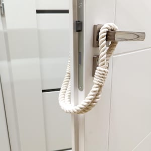 May include: White door with a silver door handle and a white rope doorstop.
