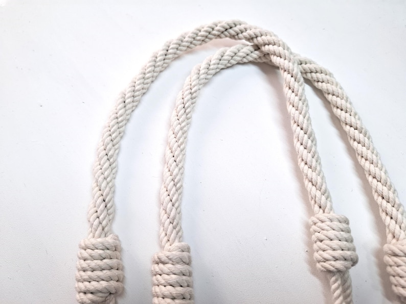 May include: Two white cotton rope handles with knots at the ends.