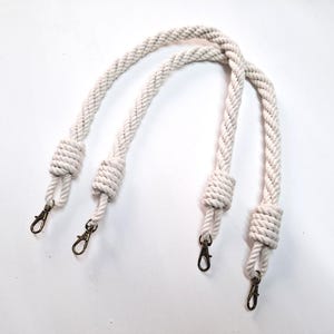 May include: Two white cotton rope handles with metal clasps. The handles are knotted at each end.