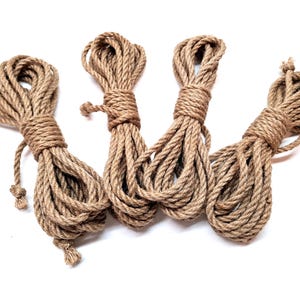 May include: Four spools of natural brown jute rope, each tied in a knot at the end. The rope is thick and textured, and the spools are arranged in a semi-circle.