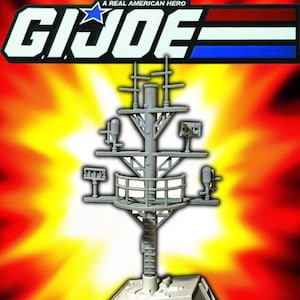 May include: A grey plastic model of a ship's mast, featuring antennas and platforms, set against a fiery yellow and orange background. The G.I. Joe logo is at the top, with the text "A REAL AMERICAN HERO".