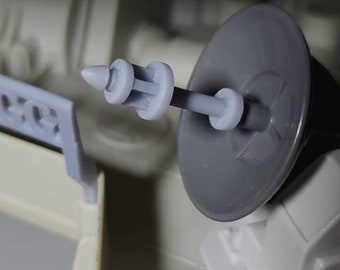 May include: A close-up of a gray plastic toy gun with a black plastic base. The gun is pointed towards the right side of the image.