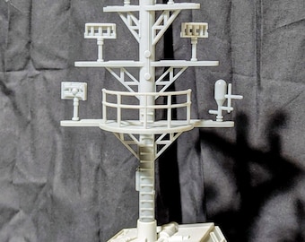 May include: A light gray model of a ship's mast, featuring multiple platforms with various antenna-like structures and a ladder. The mast is mounted on a rectangular base, with a detailed railing and support beams. The model is set against a dark gray backdrop.