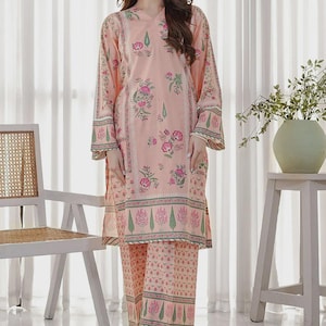 May include: A two-piece peach-colored outfit with a floral pattern. The long-sleeved top and matching pants feature pink and green floral designs. The outfit is worn with sandals. The outfit is suitable for casual wear.